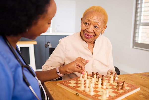 Female nurse playing chess with an older woman
