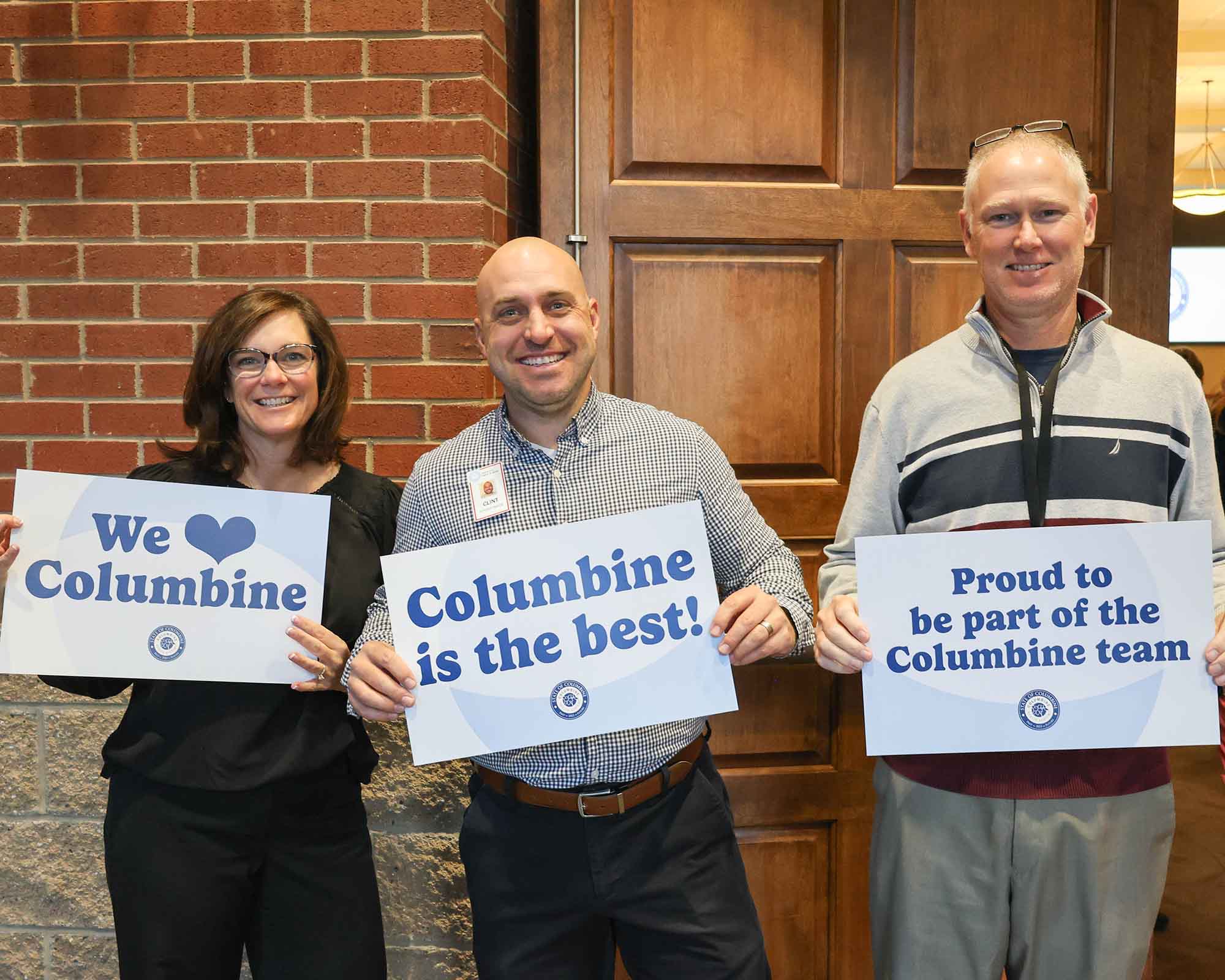 Three people holding Columbine appreciation signs