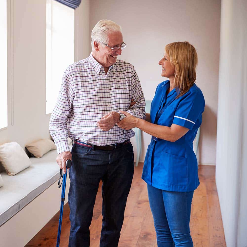 Nurse helping senior man walk using a walking stick