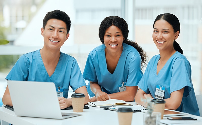 Three smiling nurses with computer