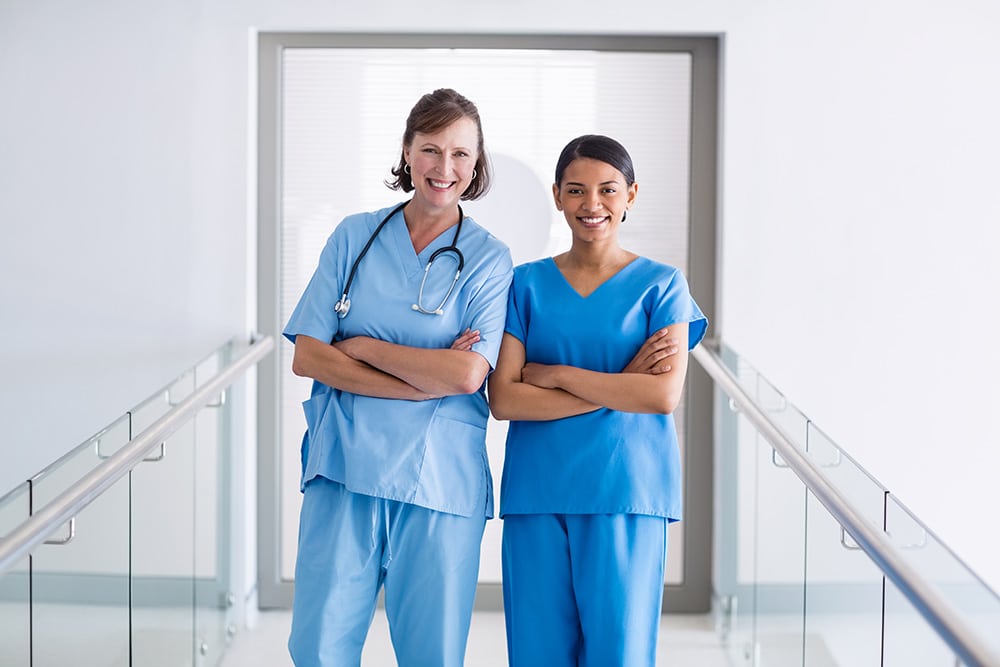Two nurses on breezeway with arms crossed
