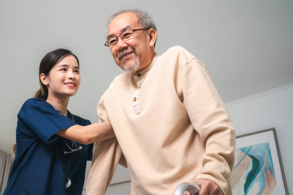 Asian physiotherapist nursing home to support old senior man patient therapy by walker