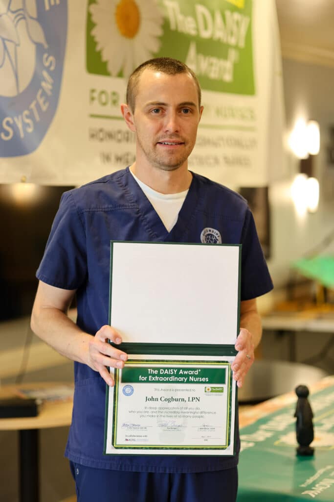 LPN John Cogbrun standing with DAISY Award