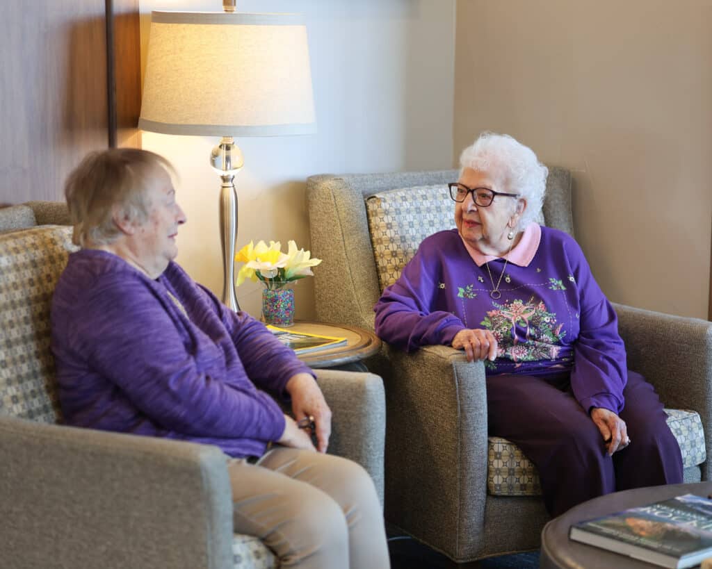 Two ladies chatting in library at The Windsor Independent Living